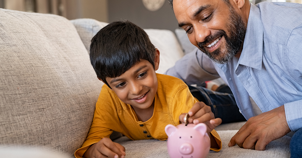 A father and son putting change into a piggy bank and smiling.