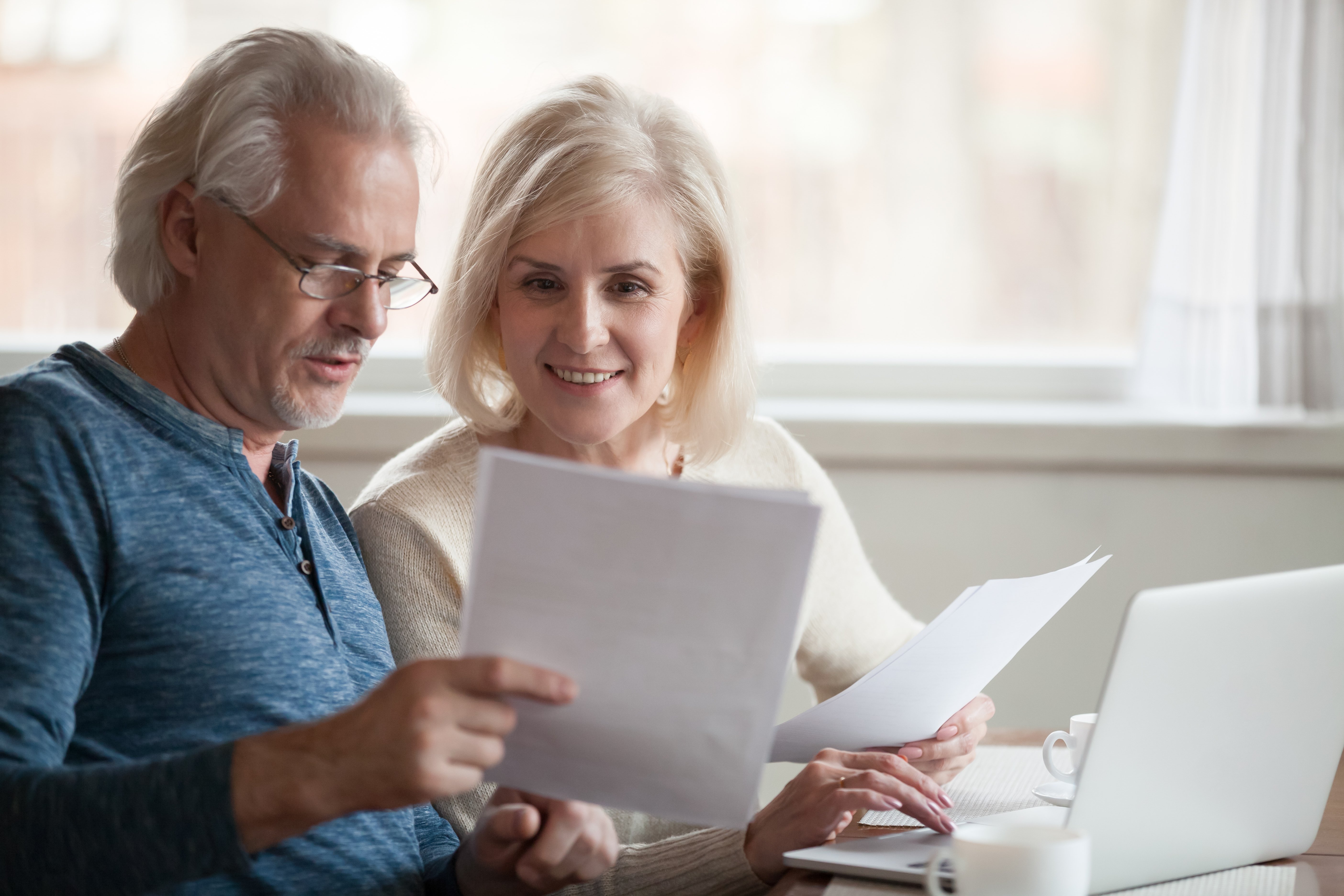 Happy older aged couple holding reading good news in document stock photo